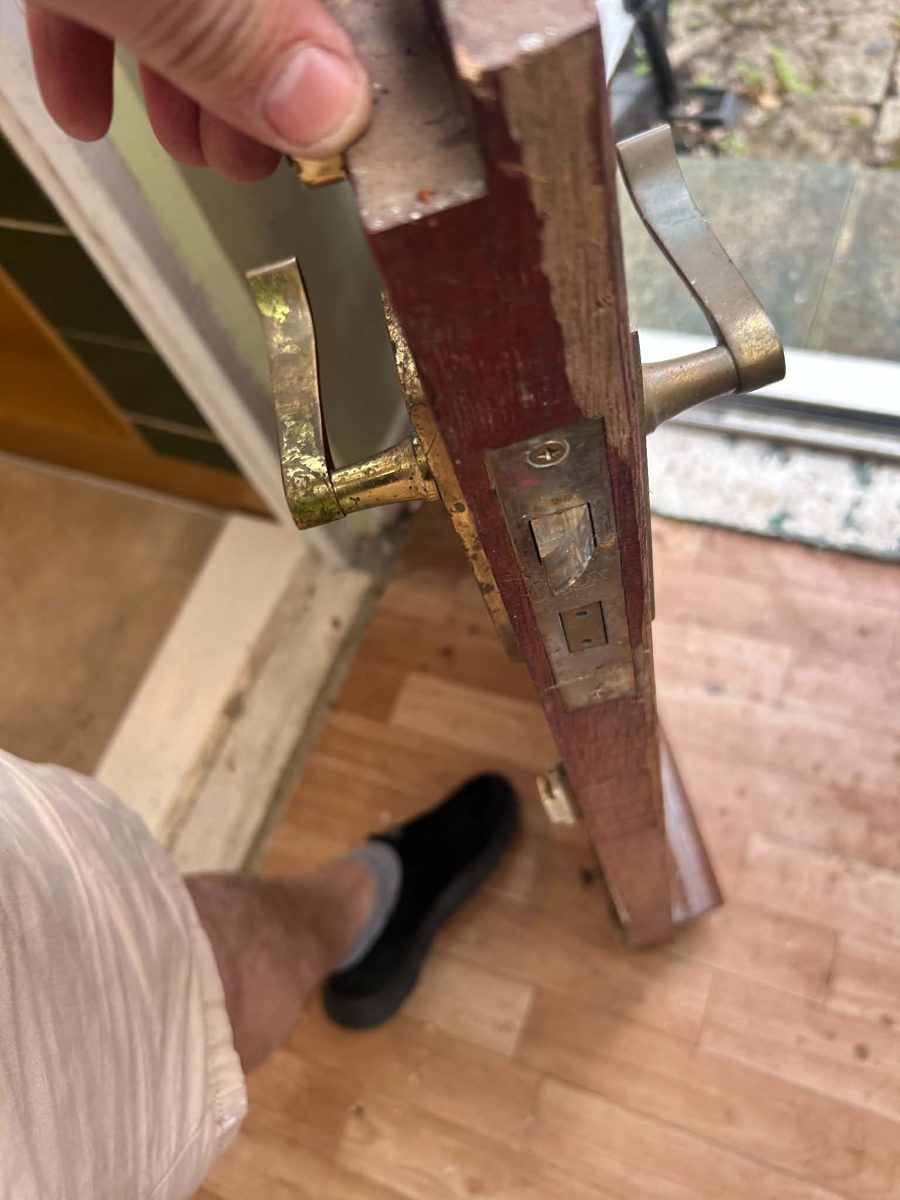 Old worn mortice sashlock and brass handles in a damaged timber door